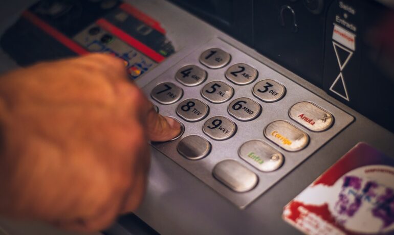 Hand entering a PIN on a bank terminal, representing strong customer authentication under PSD2